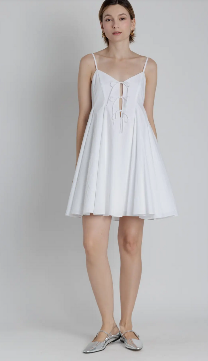 White dress with thin straps worn by a model on a plain background