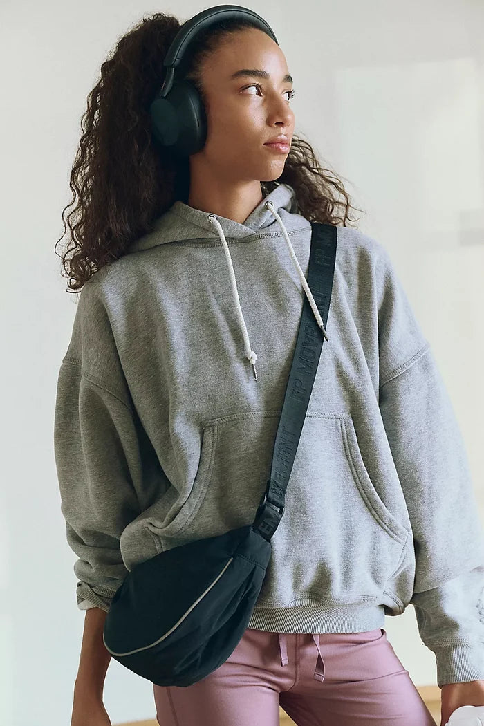 Woman holding a black sling bag with reflective detailing and an adjustable shoulder strap