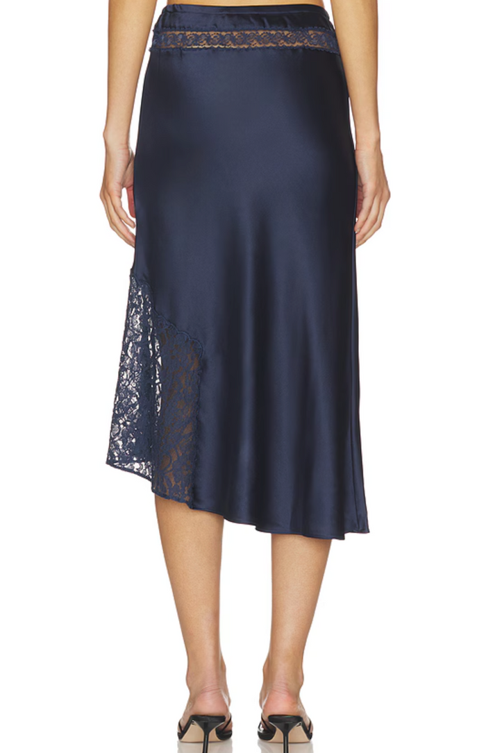 A navy blue satin midi skirt with lace trim at the waistband and side slit, shown on a model from the back against a white background.