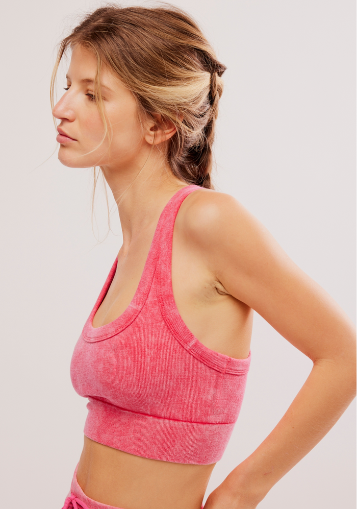 Woman wearing a electric sunset sports bra and shorts on a light background