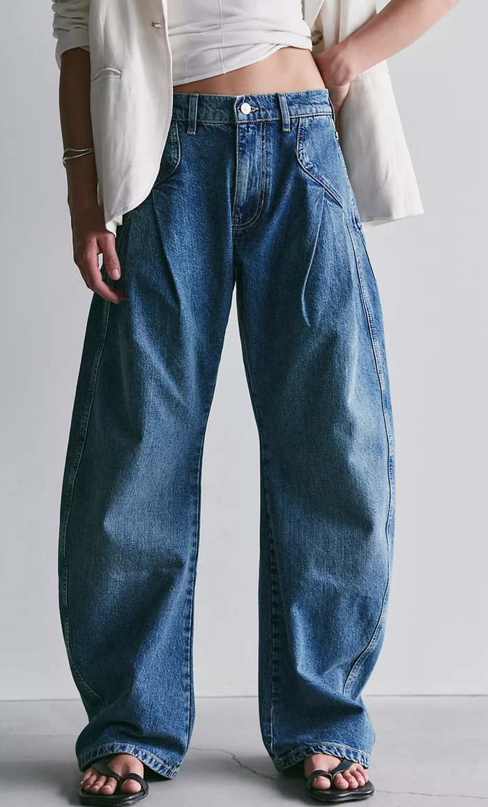 Person wearing blue jeans and a white shirt against a plain background
