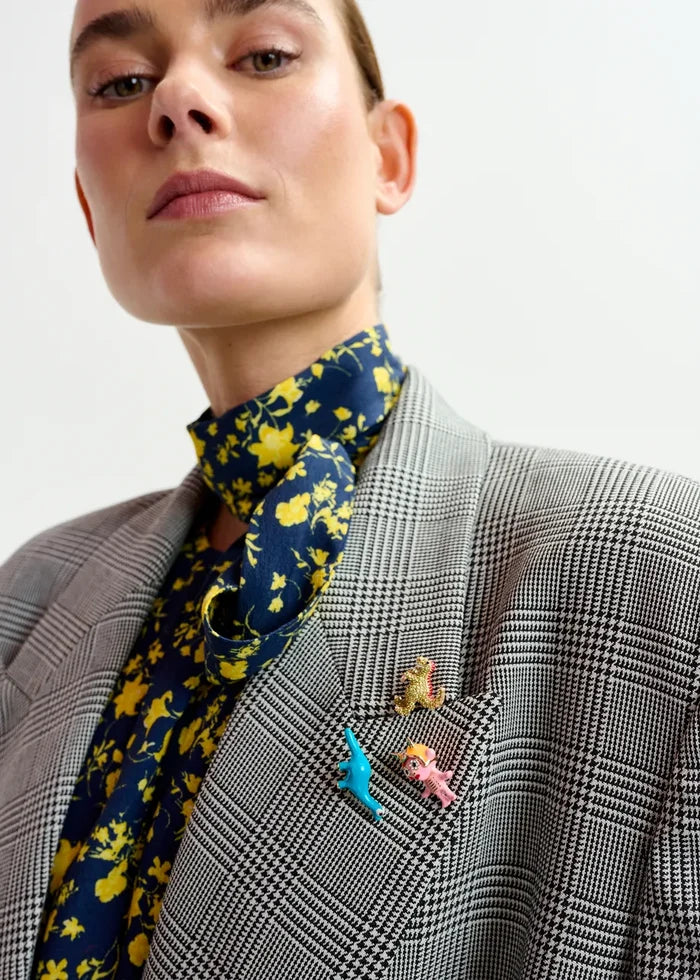 Person wearing a patterned scarf and checkered jacket with pins.