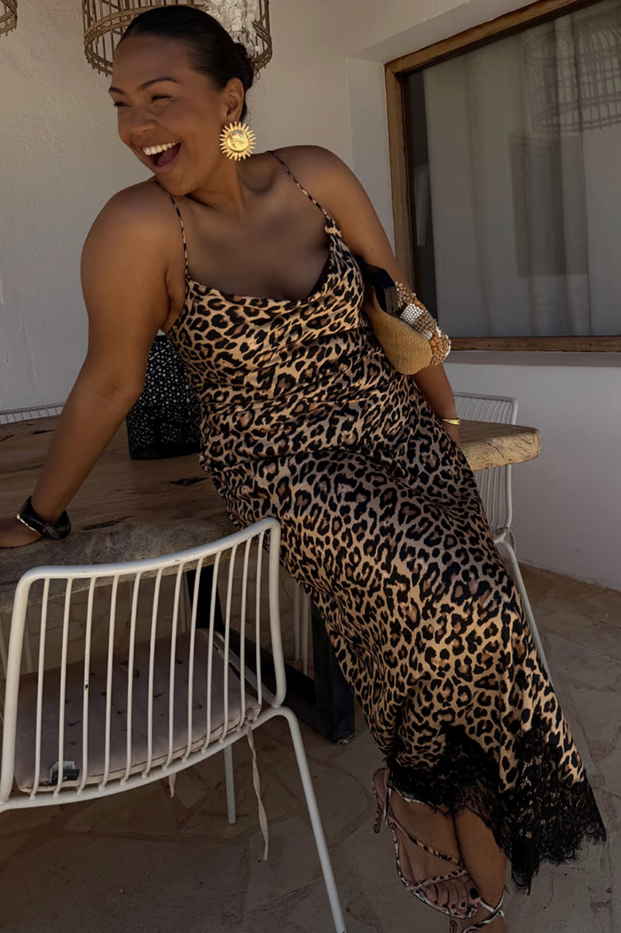 Woman in leopard print dress with gold acessories.