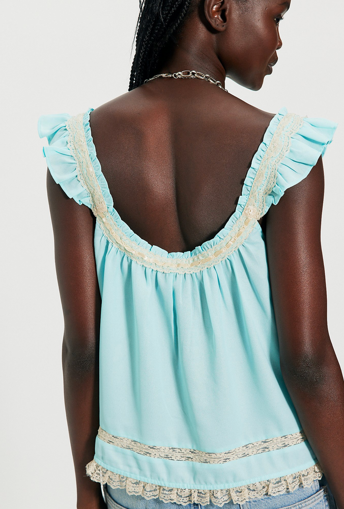 Light blue top with ruffled details on a plain background