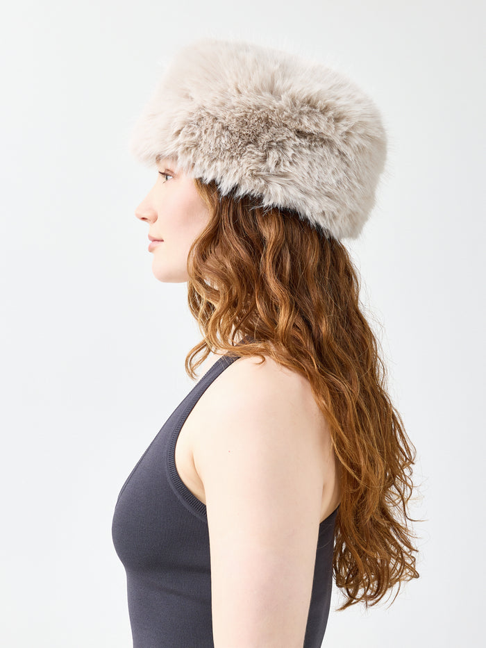 Woman wearing a beige faux fur hat on a white background