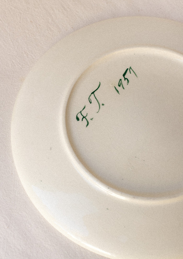 A signature on the back of a ceramic plate.