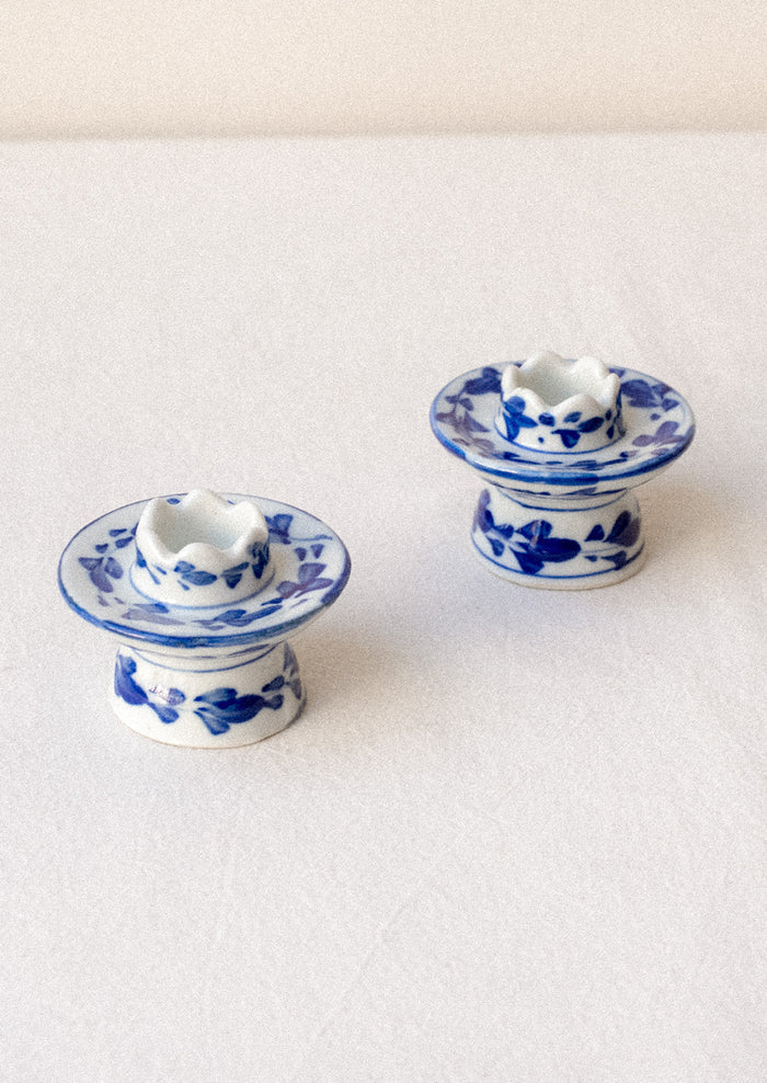 A pair of small blue and white floral print ceramic candleholders.
