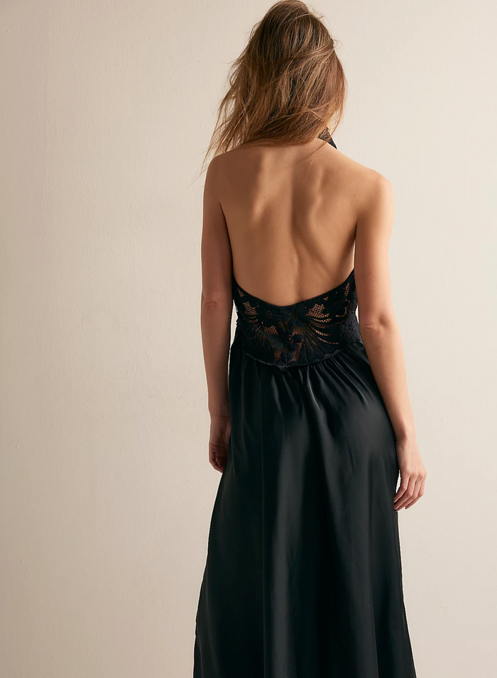 Woman wearing a black evening gown with lace detailing on a beige background