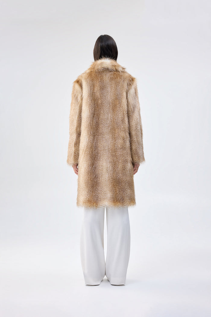 Light brown and cream faux fur coat with notch lapel and mid-length relaxed fit, worn over white wide-leg trousers, back view