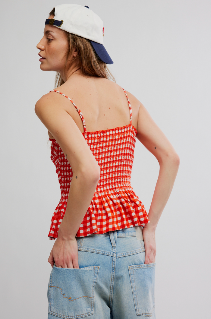 Woman wearing a red checkered top and blue jeans against a plain background