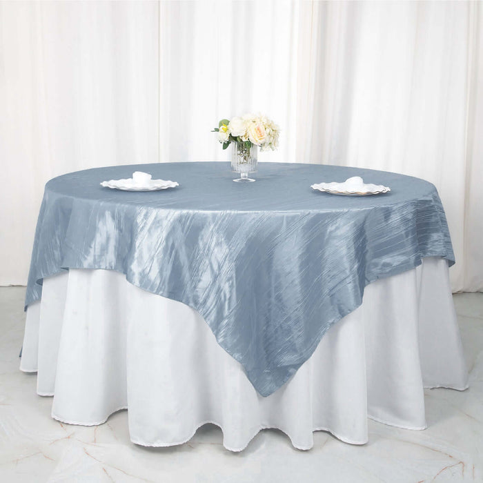 Elegant blue tablecloth draped over a round table with floral centerpiece.