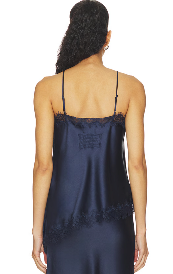A woman shown from the back wearing a navy blue satin slip dress with black lace trim along the neckline and hem, against a plain white background.