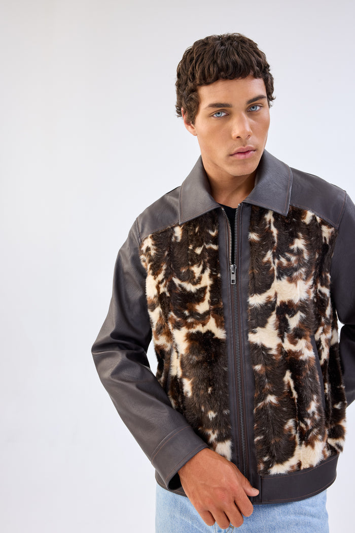 Close-up of a model wearing a brown faux leather jacket with cow-print faux fur front panel, point collar and zip-front closure