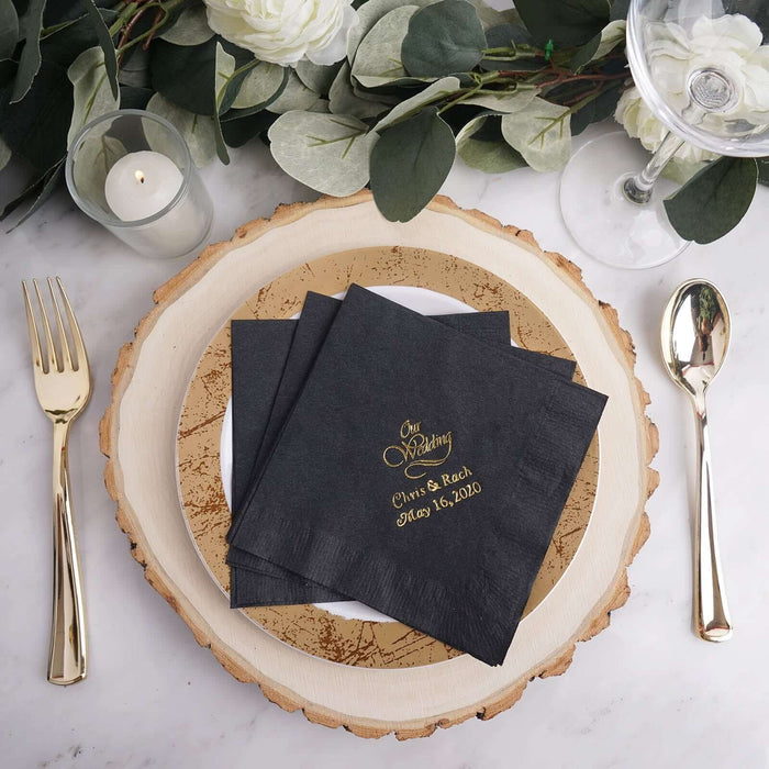 Black wedding napkins with gold text on a decorative plate.