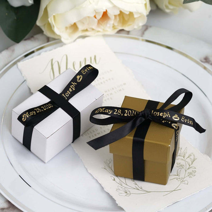 Elegant wedding favor boxes in white and gold with black ribbons.