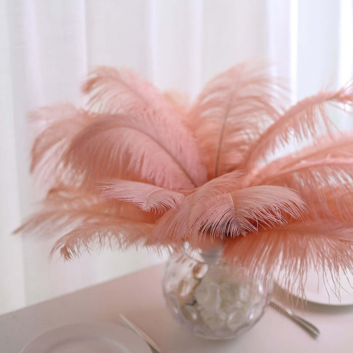 Pink feather arrangement in a glass vase on a table.