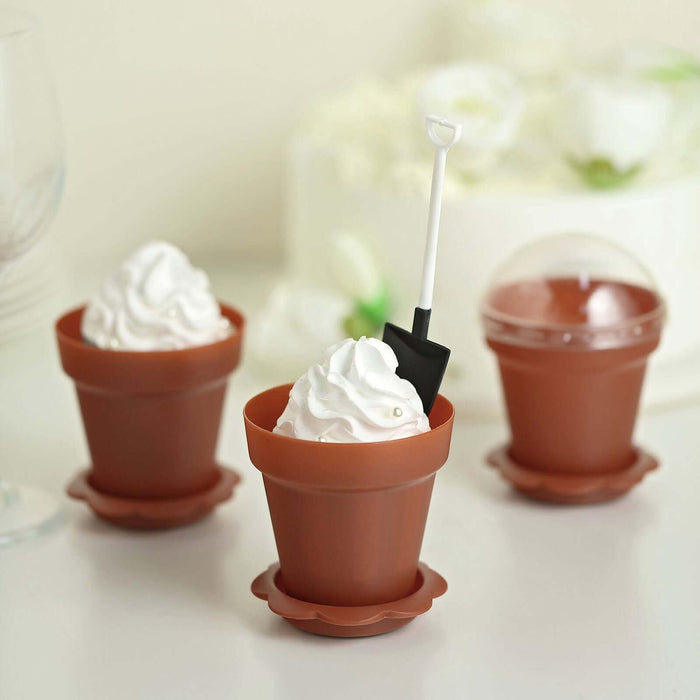 Miniature plant pots with whipped cream and a shovel spoon for dessert fun.