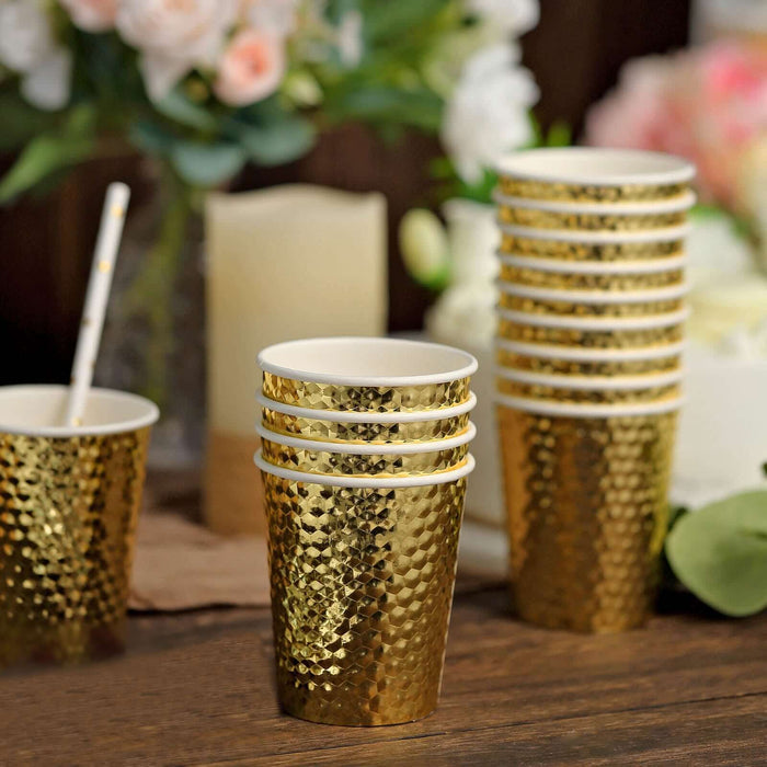 Gold textured disposable cups stacked on a table with flowers in the background.
