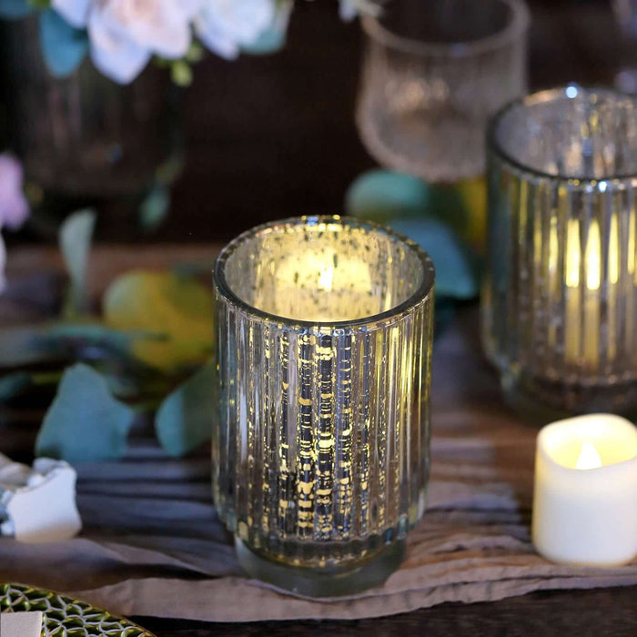 Glass candle holder with ribbed design, illuminated candle inside.