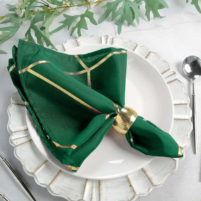 Green silk napkin with gold accents elegantly arranged on a decorative plate.