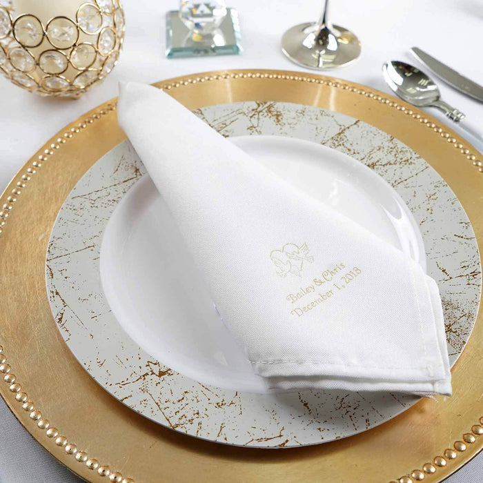 Personalized white napkin on elegant gold-rimmed plate for event dining.