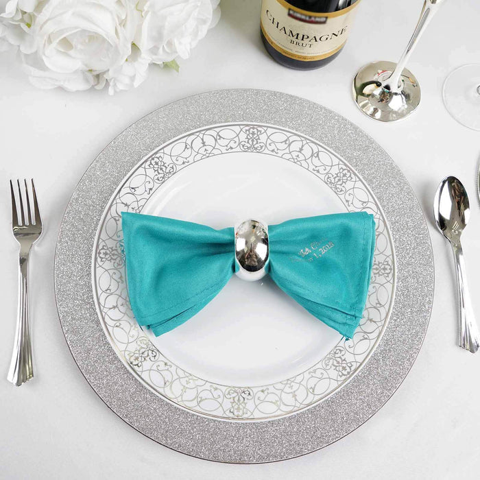Elegant teal napkin with silver holder on a decorative plate setting.