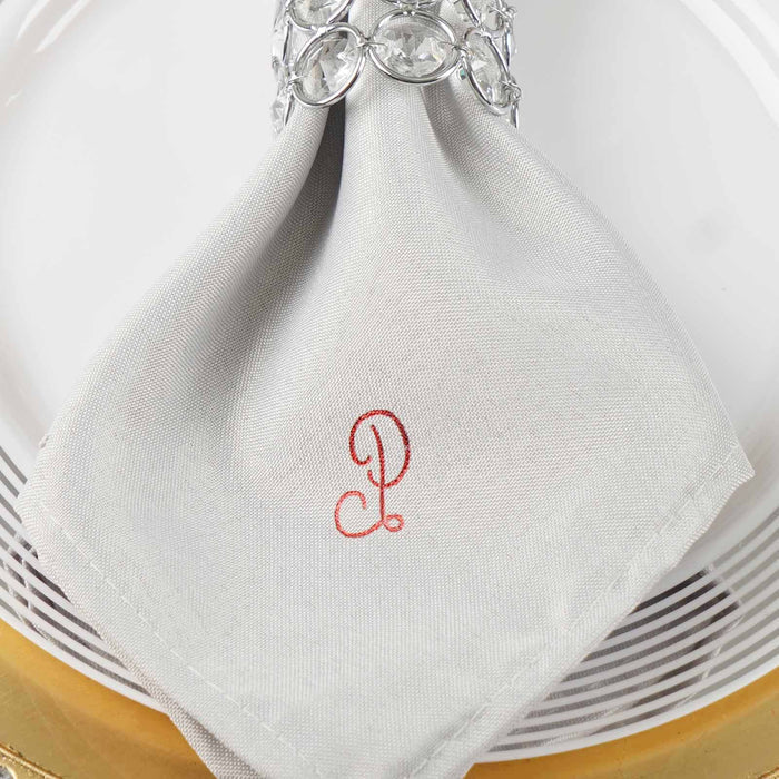 Gray napkin with embroidered letter P, elegantly styled on a plate. #whtbkgd