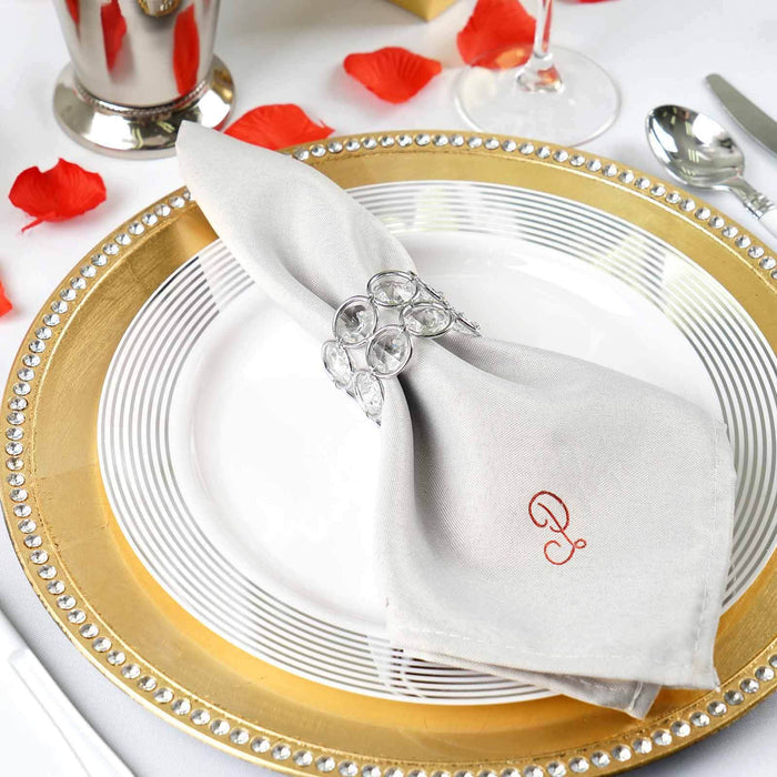Elegant table setting with a silver napkin and crystal napkin ring on a gold charger plate.