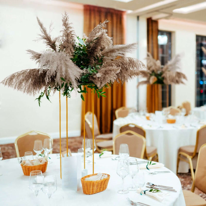 Elegant pampas grass centerpiece on a dining table in a decorated event space.