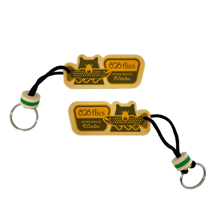 Beige foam fish and cat keychains with '828 Flies' text, green wooden beads, and silver rings