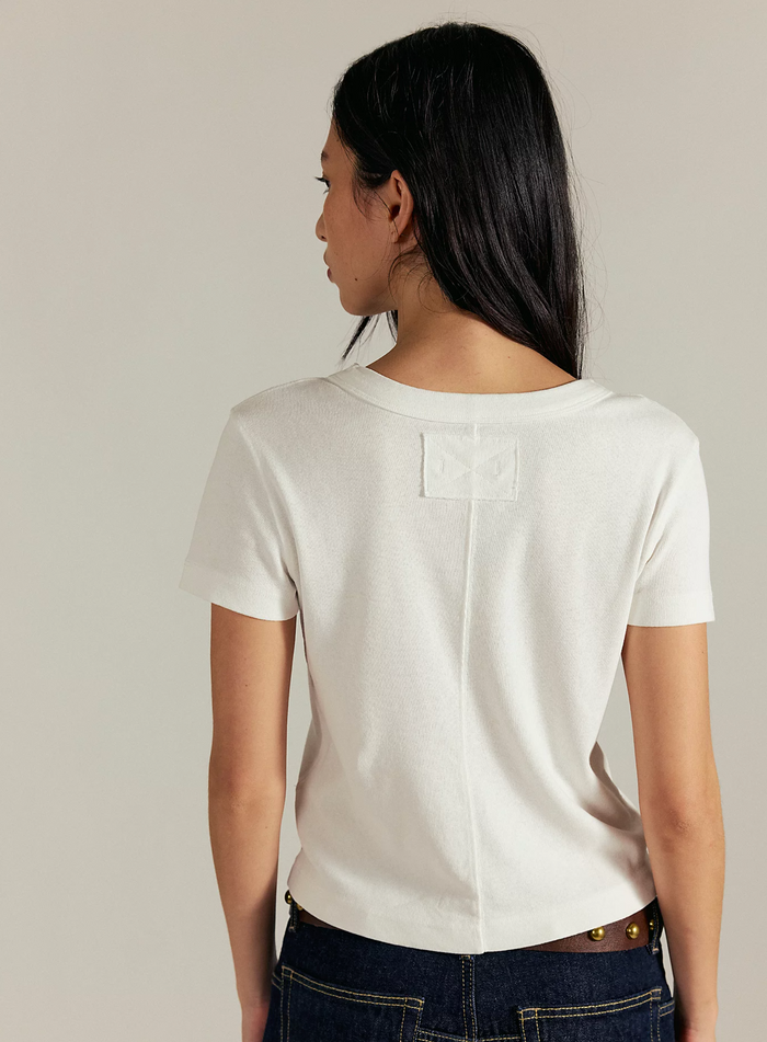 Woman wearing a Free People Ivory t-shirt against a plain background, close up view