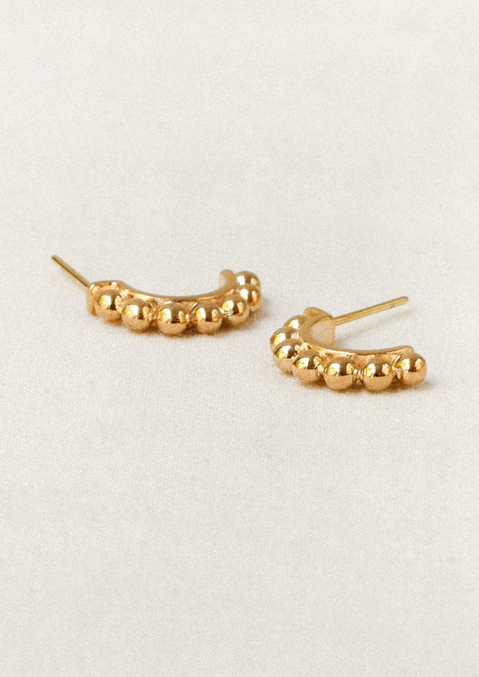 A pair of gold half hoop earrings with a beaded ball design along the tops.