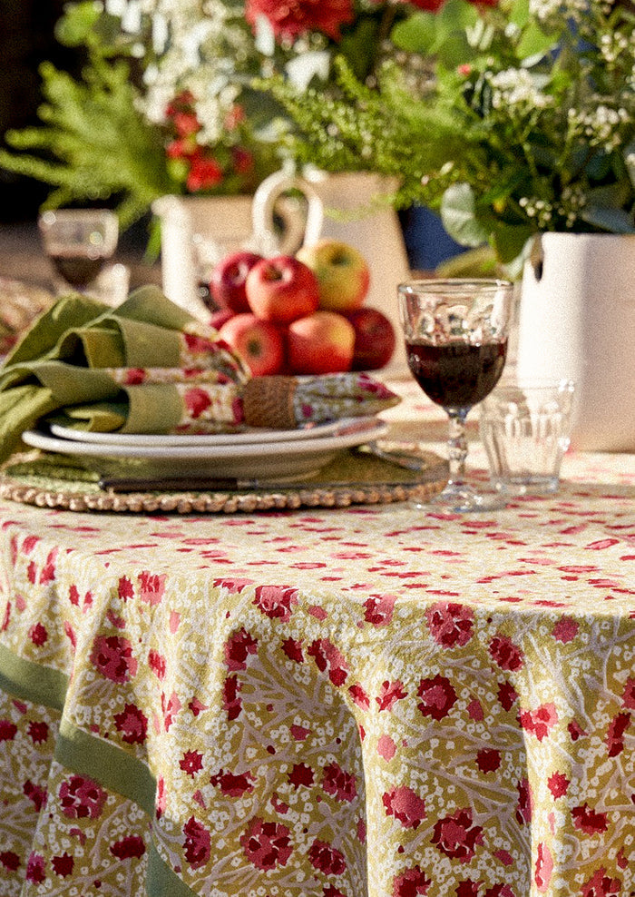 Decorative table setting with a floral tablecloth, apples, and wine glasses.