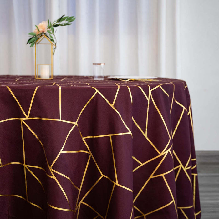 Maroon tablecloth with gold geometric pattern on a round table.