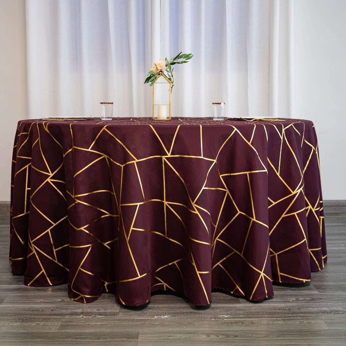 Burgundy tablecloth with gold geometric pattern on a styled table setting.