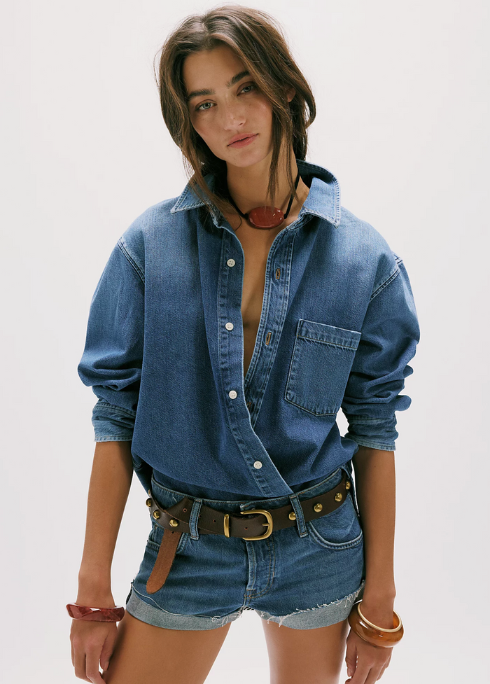 Woman wearing a denim shirt and shorts on a plain background