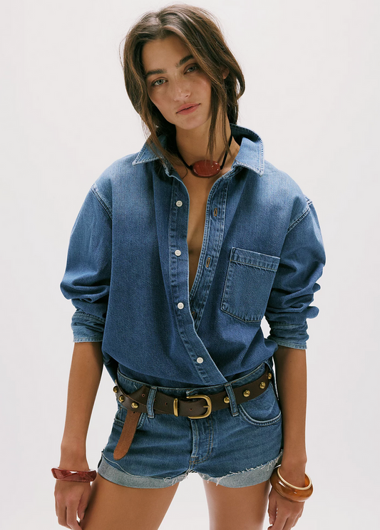 Woman wearing a denim shirt and shorts on a plain background