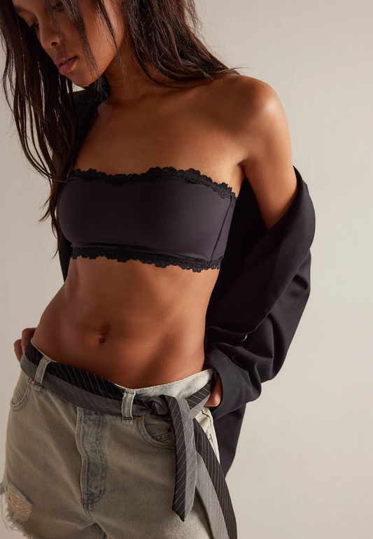 Person wearing a black strapless top and beige pants against a neutral background