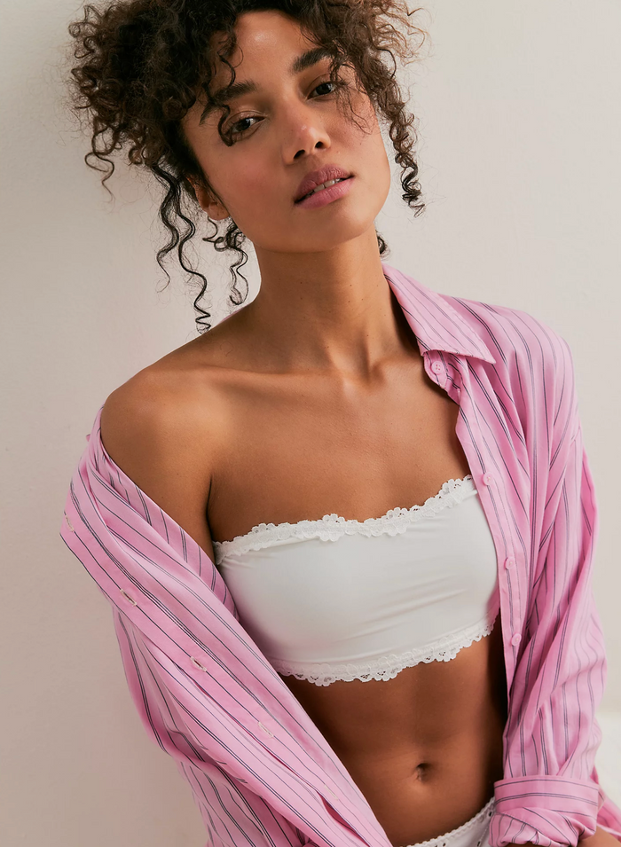 Woman wearing a white bandeau and pink shirt against a neutral background