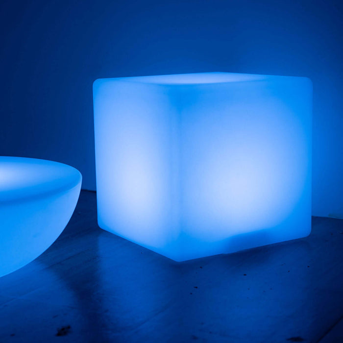 Blue LED cube light on a smooth surface.