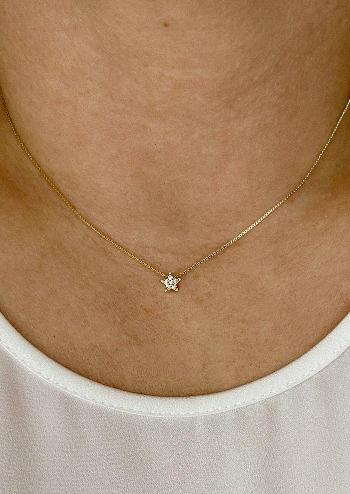 A gold box chain necklace with small gold & crystal star charm.