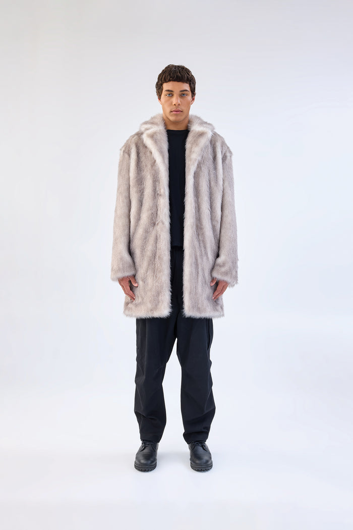 Grey faux fur coat with notch lapel and mid-length relaxed fit, worn over a black top and trousers, front view