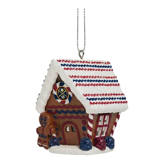 Front view decorative gingerbread house ornament. The house features a frosted roof with red and blue accents, and it is adorned with the circular Denver Nuggets logo above the doorway. A small gingerbread figure stands next to the front door.
