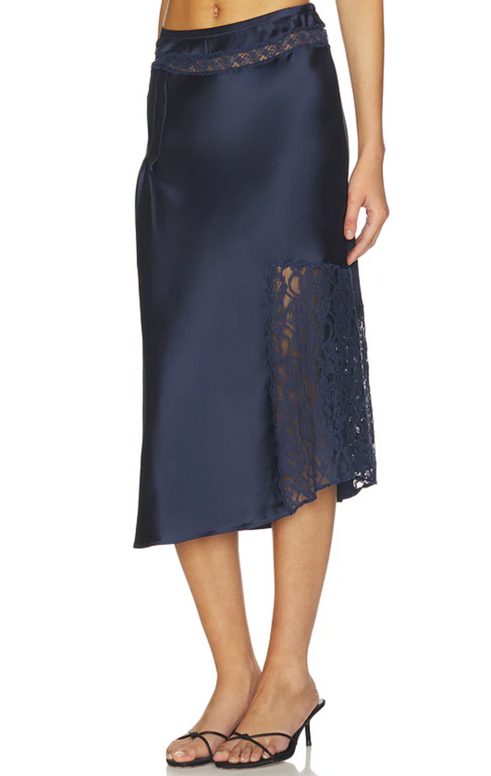 A navy blue satin midi skirt with lace trim at the waistband and a side slit, shown on a model against a white background.