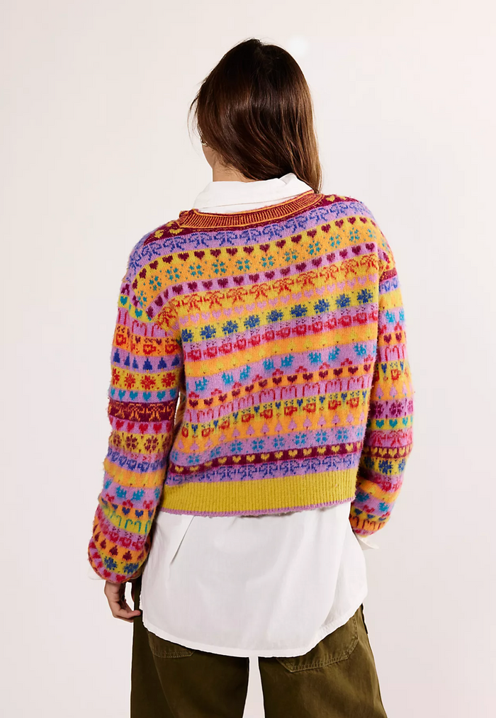Person wearing a colorful patterned sweater on a plain background