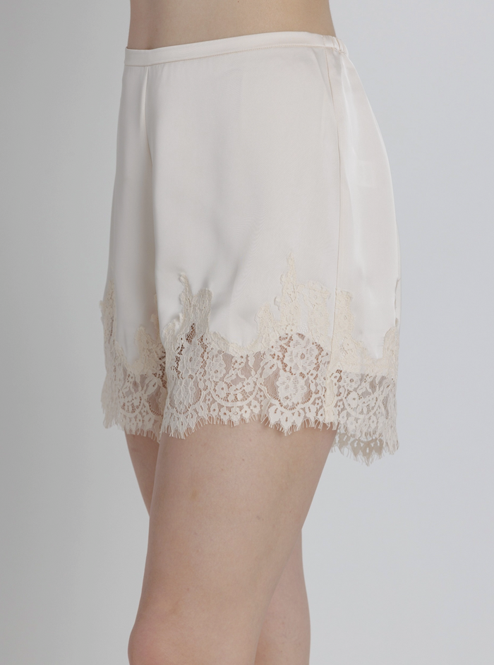 Champagne-colored lace-trimmed shorts on a plain background