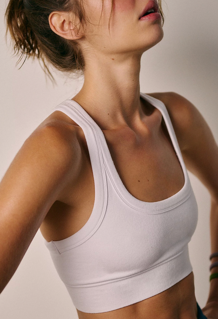 Woman wearing a white sports bra against a neutral background
