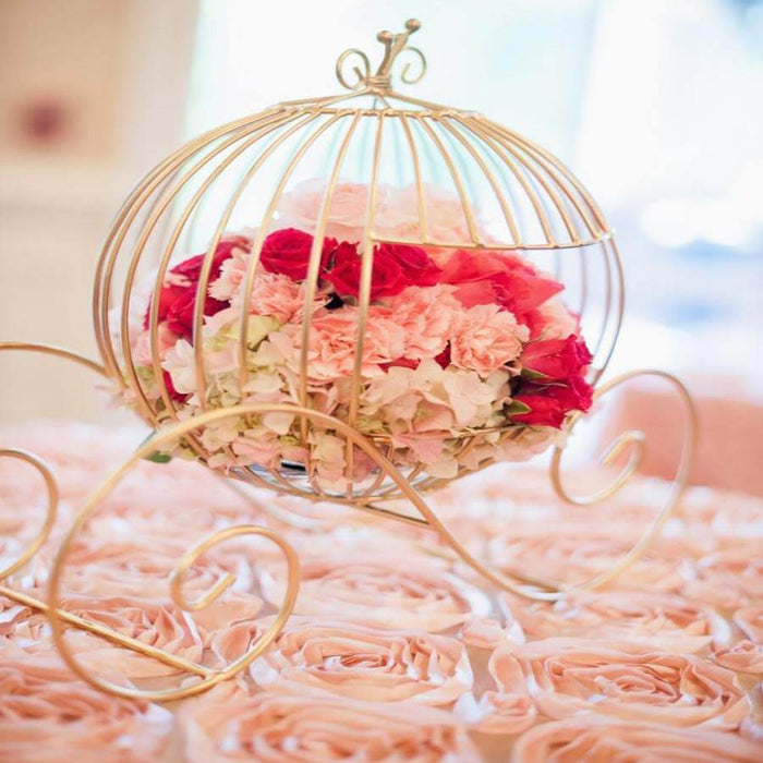 Gold birdcage with pink and red flowers on a rose-covered table.