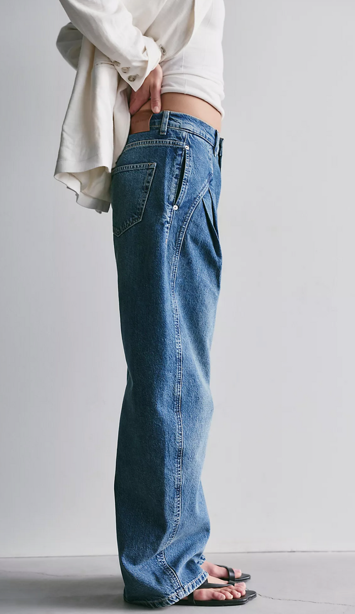 Person wearing blue jeans and a white top against a plain background
