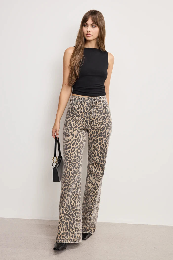 Woman wearing leopard print pants and a black top against a white background